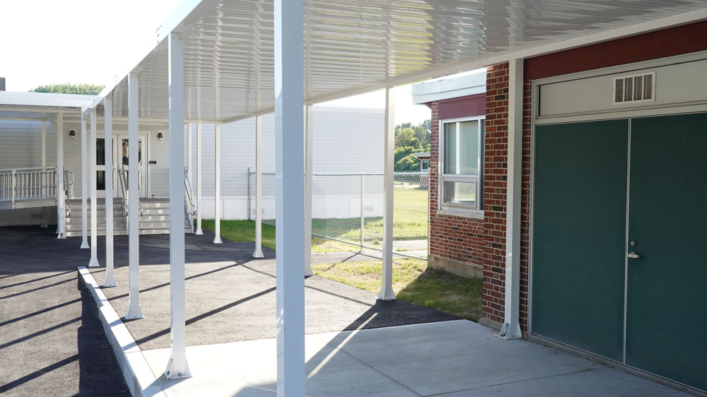 coverend outdoor entrance connecting modular classroom and existing school building.
