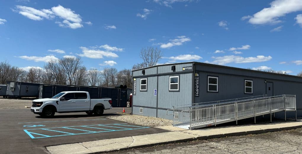 Image of a double wide office building with an ADA ramp leading to the entrance with a white pick up truck and mobile offices in the background
