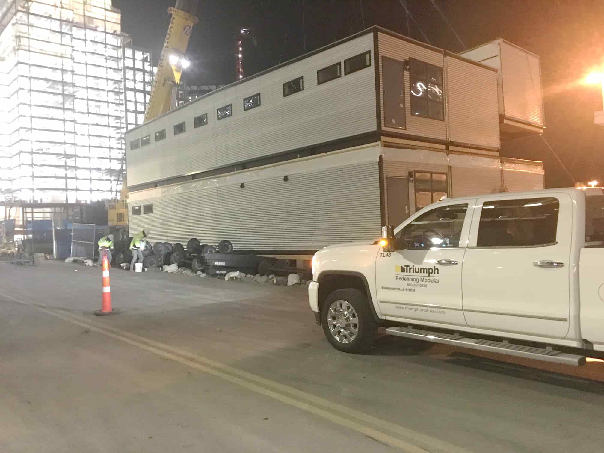 Triumph modular building being transported on-site, showcasing temporary modular construction in an urban environment.