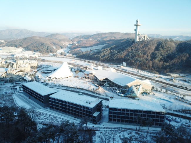 Aerial view of a snow-covered site featuring triumph modular buildings and a temporary modular construction in a mountainous landscape.