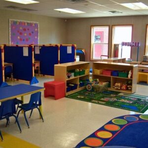 Interior classroom for preschool, with colorful rug, desks, and chairs