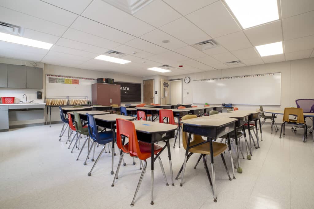Interior classroom shot with desks, chairs, and white boards