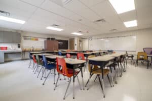 Interior classroom shot with desks, chairs, and white boards