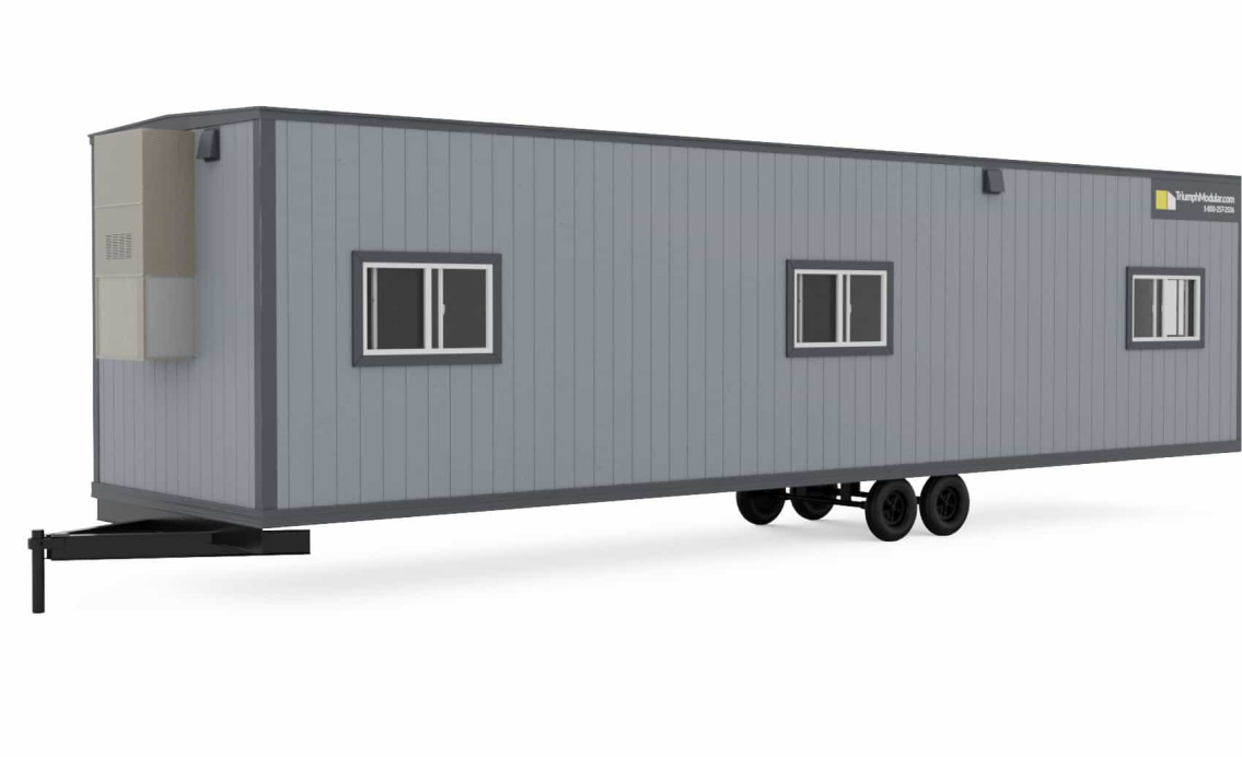 A gray temporary modular building on wheels with multiple windows, showcasing the versatility of modular construction for various needs.